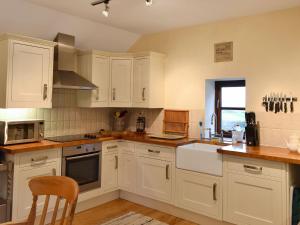 a kitchen with white cabinets and a sink at Trevellyan Barn in Lanivet