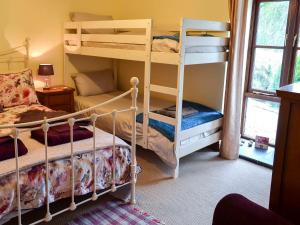 a bedroom with two bunk beds and a window at Trevellyan Barn in Lanivet