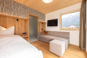 a bedroom with a bed and a couch and a window at Pension Gulla - Ferienhaus Appartements B&B in Neustift im Stubaital
