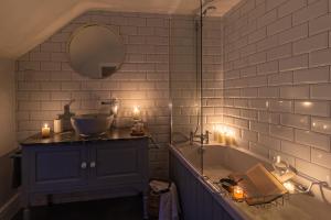 a bathroom with a tub and a sink and candles at Garth Cottage in West Ayton in Scarborough