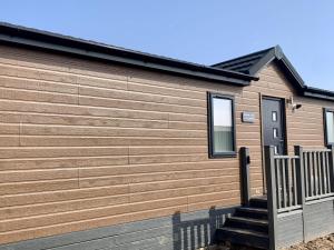 a house with a wooden wall with a wooden staircase at Cherry Blossom 43 Hot Tub in Garton