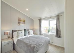 a white bedroom with a bed and a window at Cherry Blossom 48 Hot Tub in Garton