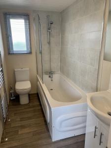a bathroom with a tub and a toilet and a sink at Elm 34 Hot Tub in Garton