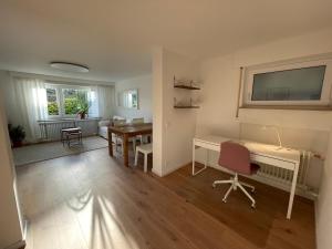 ein Wohnzimmer mit einem Schreibtisch und einem Tisch in der Unterkunft Schöne Wohnung direkt am Naturpark in Leinfelden-Echterdingen
