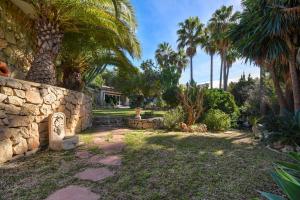 een tuin met palmbomen en een stenen muur bij Casa Chimo in Moraira