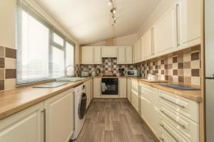 a large kitchen with white cabinets and a window at Birch 24 Hot Tub in Garton