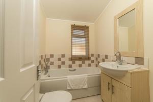 a bathroom with a tub and a sink and a toilet at Birch 24 Hot Tub in Garton