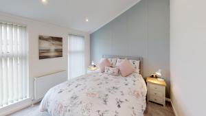 a white bedroom with a bed with pink pillows at Beech 28 Hot Tub in Garton