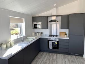 a kitchen with black and white cabinets and a sink at Elm 35 Hot Tub in Garton