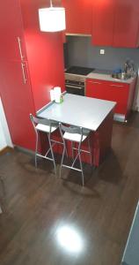 una cocina con armarios rojos y una mesa y sillas blancas. en Ático,loft ,duplex, en Madrid