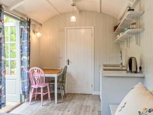 uma cozinha com mesa e cadeiras num quarto em Fig Tree Shepherds Hut em Bridport