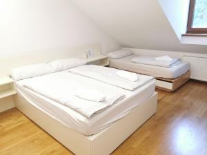 two beds in a room with white walls and wooden floors at Rooms Sincere 1830 in Ljubljana