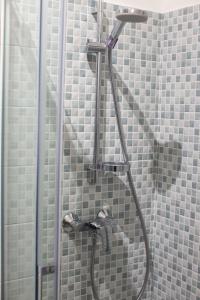 a shower in a bathroom with gray tiles at Dimora del Sole - Intero Appartamento in LʼAquila