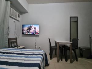 1 dormitorio con cama, mesa y TV en la pared en Macks Awesome Place 204 NetflixFastWifi, en Manila