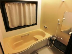 a bathroom with a tub and a sink and a mirror at 潮風room@SUN(シオカゼルームアットサン) in Minamiboso