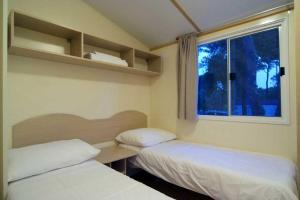 two beds in a room with a window at Seaside Tkon Mobile Homes in Tkon