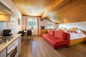 a living room with a red couch and a bed at Aparthotel Stadler in Flachau