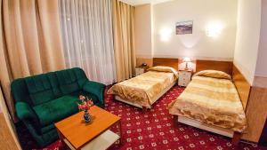 a hotel room with two beds and a green couch at Reikartz Dostar Karaganda in Karagandy
