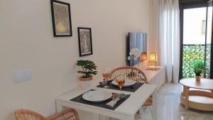 a dining room with a white table and chairs and a table and a dining room at Sherryflat Trébol - Parking in Jerez de la Frontera