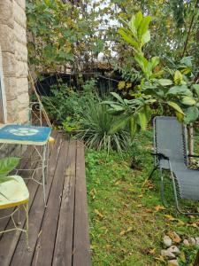 una terraza de madera con mesa y sillas en un jardín en סוויטת פינת השקד en Rosh Pinna