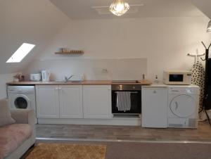 uma cozinha com armários brancos e um forno com placa de fogão em Hill View Studio em Hawick