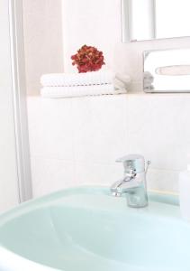 a white bathroom with a sink and a faucet at Lindenhotel Stralsund in Stralsund