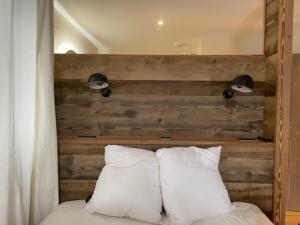 een houten hoofdeinde met twee witte kussens op een bed bij Magnifique chalet sur les pistes, le Paradis c'est là! in La Toussuire