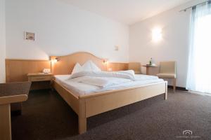 um quarto com uma cama grande e lençóis brancos em Kreuzstein Bed&Breakfast em Appiano sulla Strada del Vino