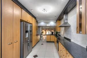 cocina grande con armarios de madera y electrodomésticos de acero inoxidable en The Royal Residence, en Johannesburgo