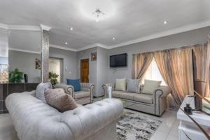 sala de estar amplia con sofá y TV en The Royal Residence, en Johannesburgo