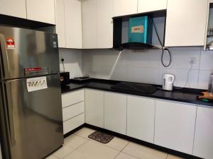 a kitchen with a stainless steel refrigerator and white cabinets at JB City Pinnacle Tower @Pinpoint Vacation Homes in Johor Bahru