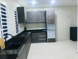 una cocina con electrodomésticos de acero inoxidable y encimeras negras en SUNNY HOMESTAY KUALA SELANGOR en Kuala Selangor