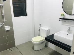 a white bathroom with a toilet and a sink at SUNNY HOMESTAY KUALA SELANGOR in Kuala Selangor