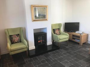 a living room with two chairs and a fireplace at Kingsmills Cottages in Artrea