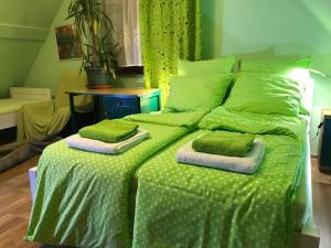 a green bed with green sheets and pillows on it at Leśniczówka domek sauna jeziorko w lesie na wyłączność in Straszydle