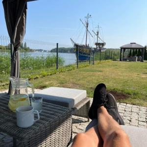 a person sitting on a table with their feet up on a table with a drink at Willa Aura Mare in Dziwnów