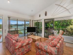 a living room with two couches and a television at Pohutukawa on Paku - Tairua Holiday Home in Tairua