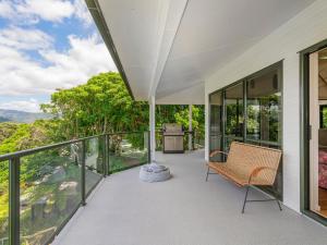 an expansive balcony with a chair and a view at Pohutukawa on Paku - Tairua Holiday Home in Tairua