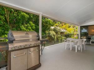 an outdoor patio with a grill and a table at Pohutukawa on Paku - Tairua Holiday Home in Tairua