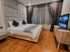 um quarto com uma cama grande e uma televisão de ecrã plano em Vortex Suites KLCC By Sweet.Home em Kuala Lumpur
