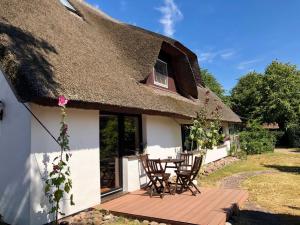 a thatch roofed cottage with a wooden deck at Haus 1795 Stieglitz in Wustrow