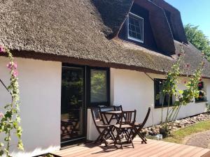 a house with two chairs and a thatched roof at Haus 1795 Stieglitz in Wustrow