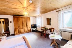 a living room with a wooden ceiling and a tv at Pension Luger in Aschau im Chiemgau