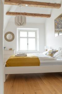 a white bedroom with a bed with a yellow blanket at Beautiful Penthouse - City Center in Graz