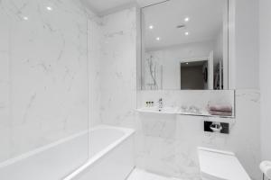 ein weißes Badezimmer mit Badewanne und Waschbecken in der Unterkunft Elliot Oliver - Chic 2 Bedroom Town Centre Apartment in Cheltenham