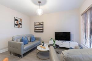 a living room with a couch and a tv at Elliot Oliver - Chic 2 Bedroom Town Centre Apartment in Cheltenham