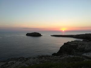 een zonsondergang boven de oceaan met rotsen in het water bij MandorleOlio in Polignano a Mare