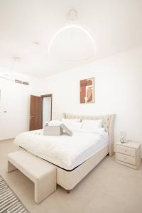 a white bedroom with a large bed and a light fixture at Spacious modern 2 bedroom apartment in Dubai