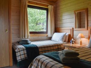 two beds in a log cabin with a window at The Shed in Woolfardisworthy