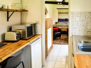 uma cozinha com um micro-ondas e uma sala de estar em The Bothy em Hockham